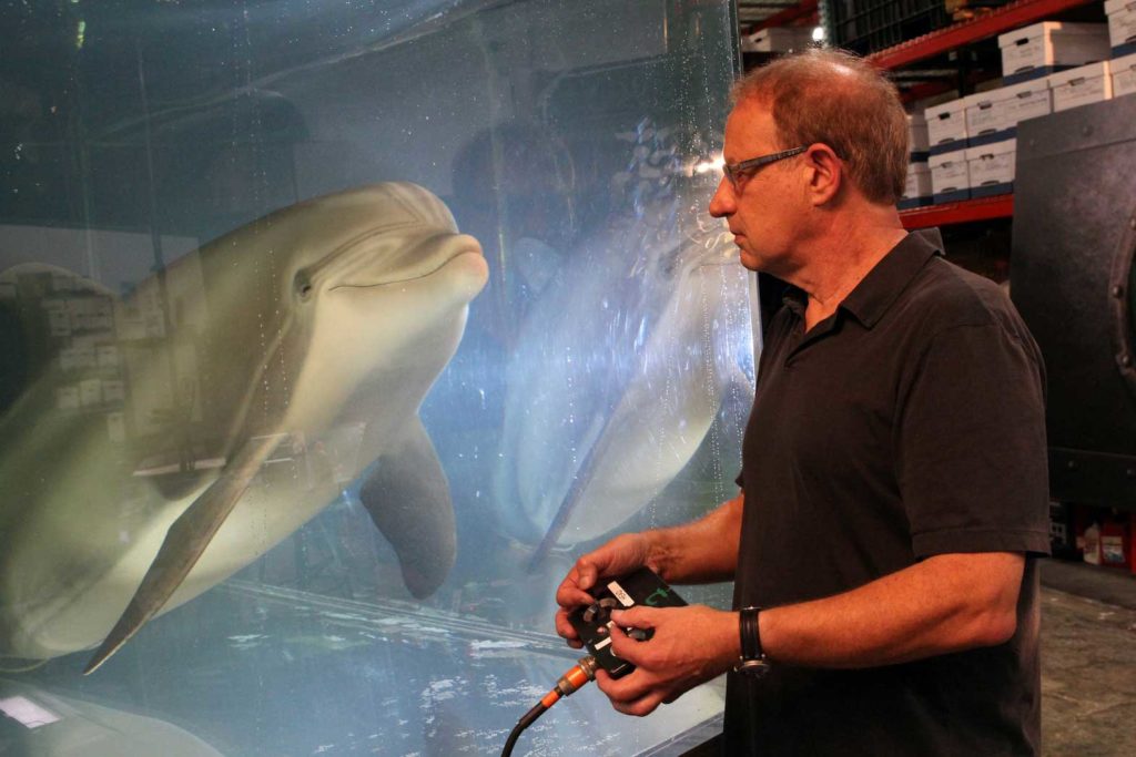Walt Conti, founder and CEO of Edge Innovations, uses a handheld controller to move an animatronic dolphin in a tank at the company's warehouse in Fremont, California, U.S., September 30, 2020. Picture taken September 30, 2020. REUTERS/Nathan Frandino