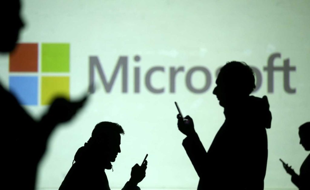 Silhouettes of mobile users are seen next to a screen projection of Microsoft logo in this picture illustration taken March 28, 2018. REUTERS/Dado Ruvic/Illustration/File Photo