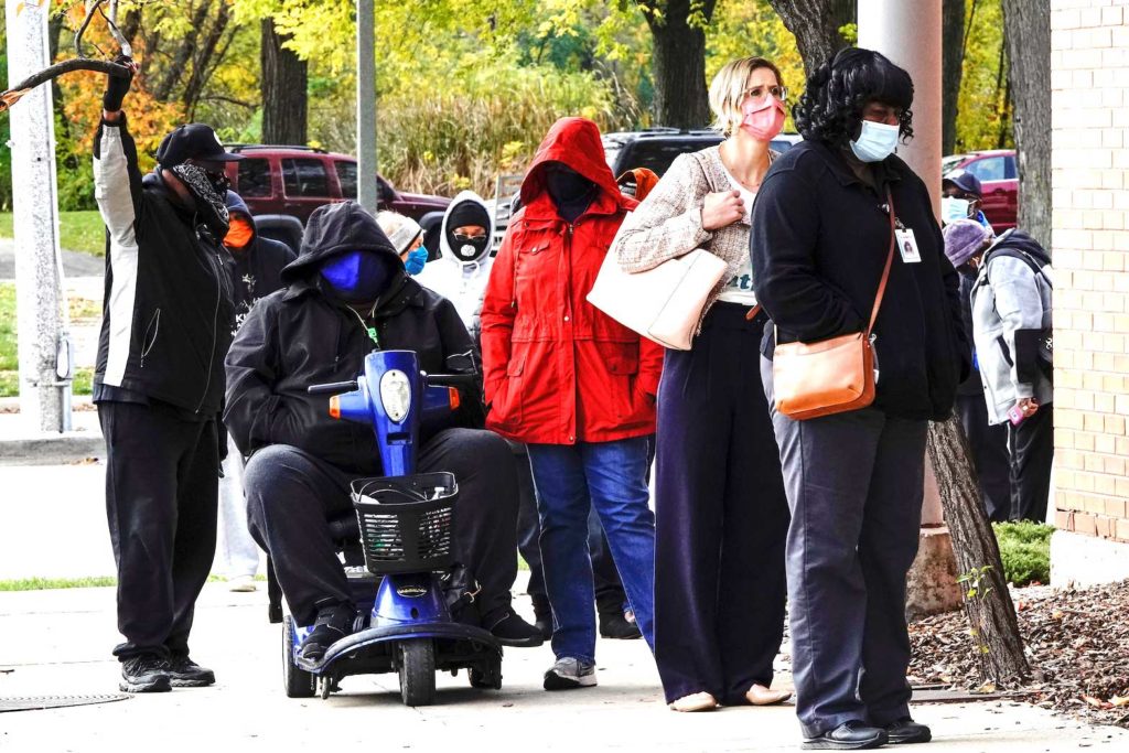 People wearing protective masks queue to enter a polling site at the Milwaukee Public Library?s Washington Park location in Milwaukee, on the first day of in-person voting in Wisconsin, U.S., October 20, 2020. REUTERS/Bing Guan