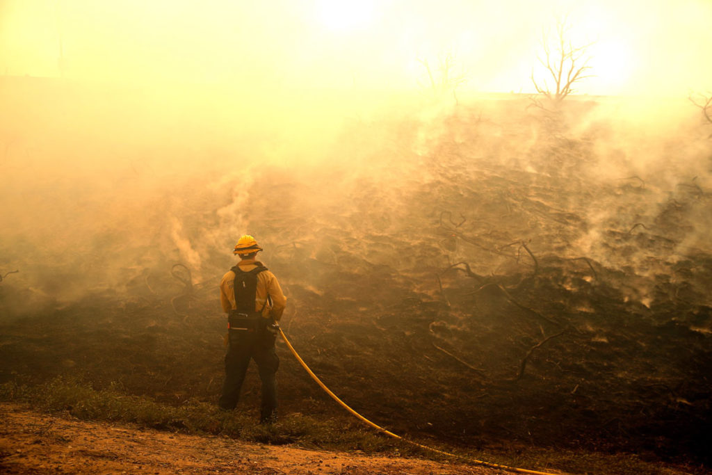 A firefighter uses a hose as the Silverado Fire approaches, near Irvine, California, U.S. October 26, 2020. REUTERS/Mike Blake