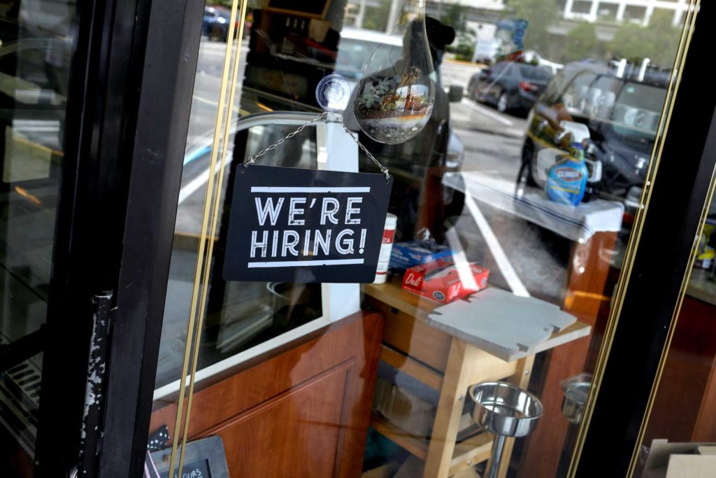 A "We're Hiring" sign advertising jobs is seen at the entrance of a restaurant in Miami, Florida, U.S., May 18, 2020. REUTERS/Marco Bello/File Photo