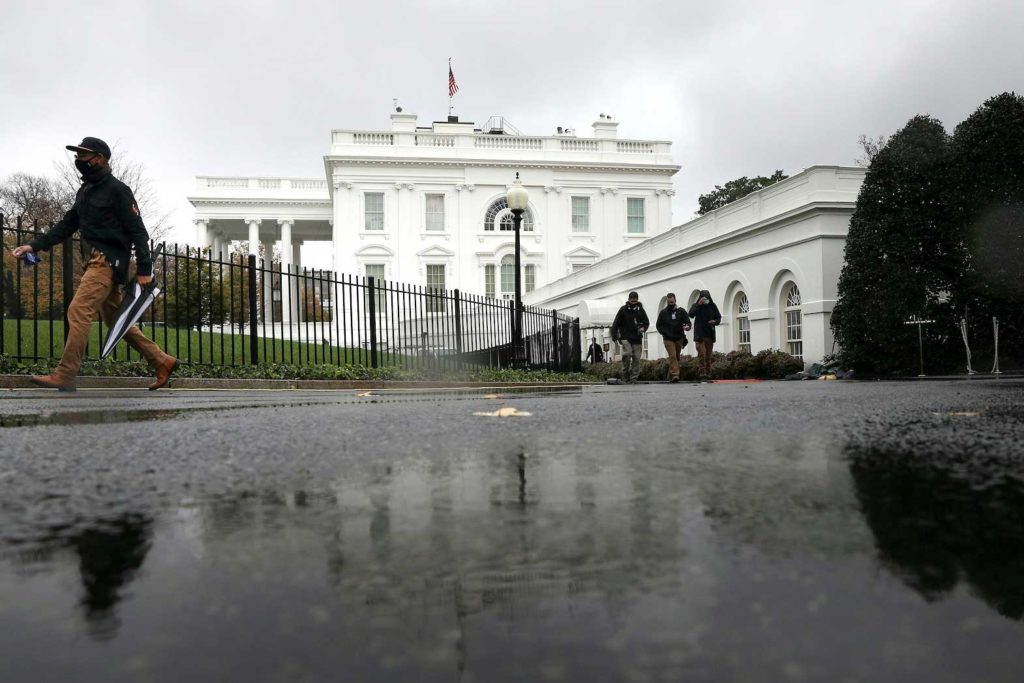 White House staff and journalists walk across the North Lawn Driveway as rain falls over the White House during a storm in Washington, U.S., November 12, 2020. REUTERS/Tom Brenner/File Photo