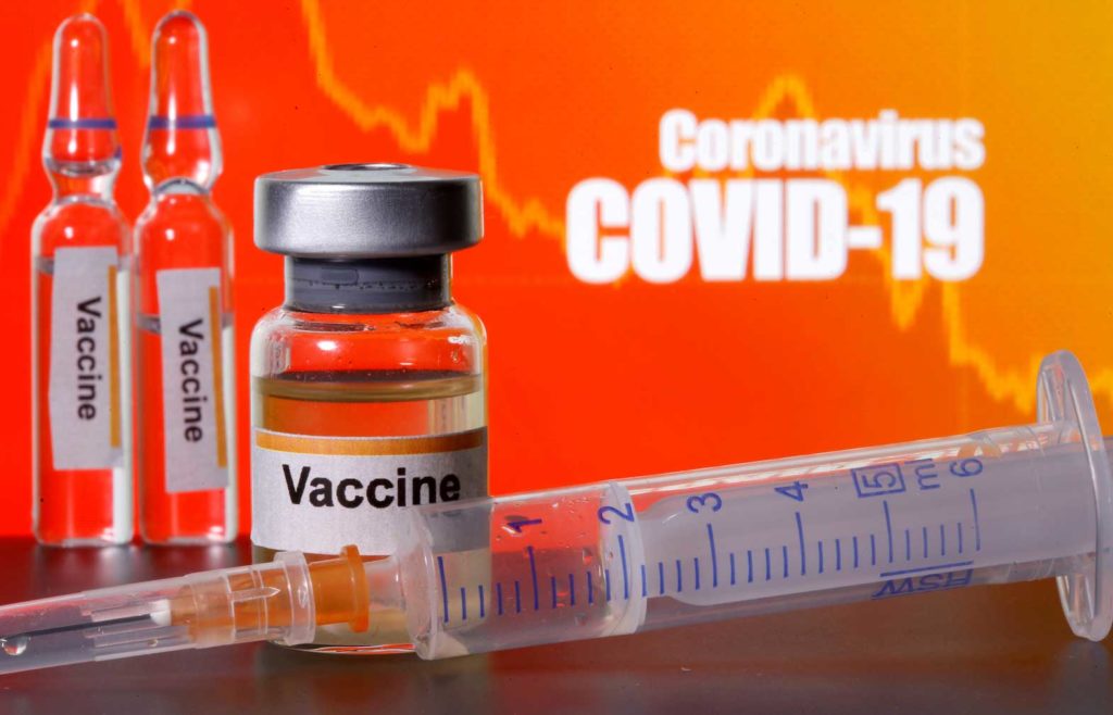 Small bottles labelled with "Vaccine" stickers stand near a medical syringe in front of displayed "Coronavirus COVID-19" words in this illustration taken April 10, 2020. REUTERS/Dado Ruvic/Illustration/File Photo
