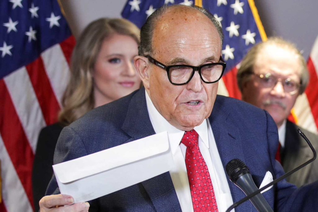 Former New York City Mayor Rudy Giuliani, personal attorney to U.S. President Donald Trump, holds what he identified as a replica mail-in ballot as he speaks about the 2020 U.S. presidential election results during a news conference in Washington, U.S., November 19, 2020. REUTERS/Jonathan Ernst/File Photo