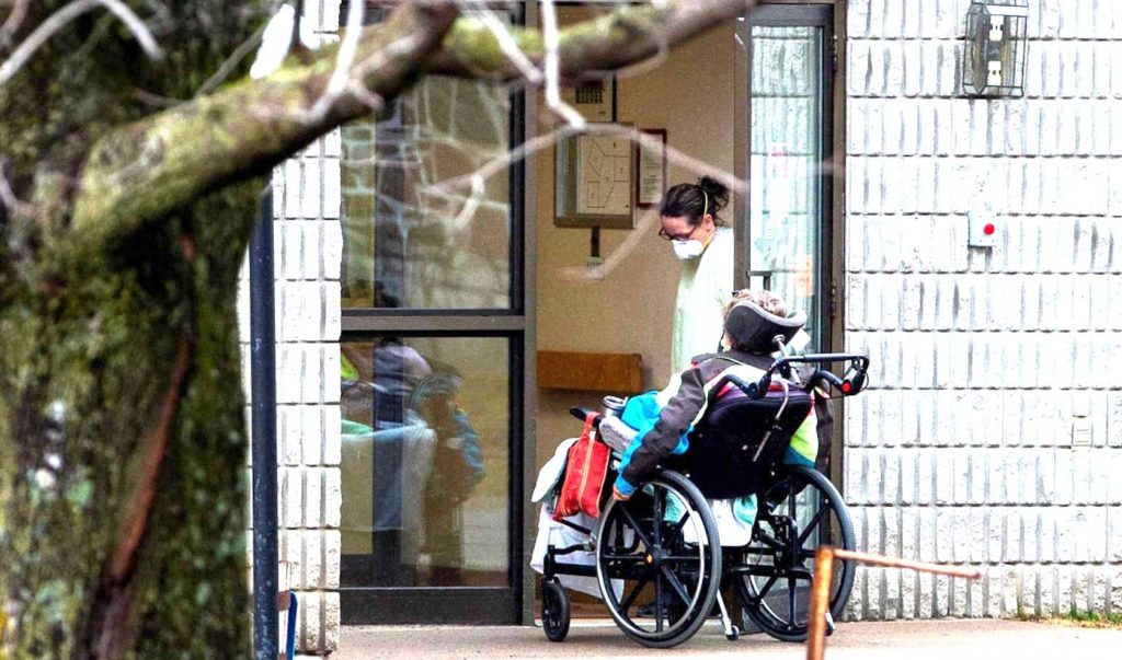  A woman opens the door to a person in a wheelchair at Pinecrest Nursing Home after several residents died and dozens of staff were sickened due to the coronavirus disease (COVID-19), in Bobcaygeon, Ontario, Canada, on March 30, 2020. (Carlos Osorio/REUTERS)