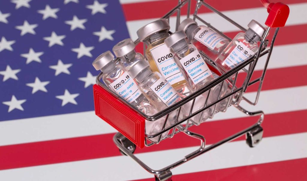 A small shopping basket filled with vials labeled "COVID-19 - Coronavirus Vaccine" is placed on a U.S. flag in this illustration taken November 29, 2020. Picture taken November 29, 2020. REUTERS/Dado Ruvic/Ilustration