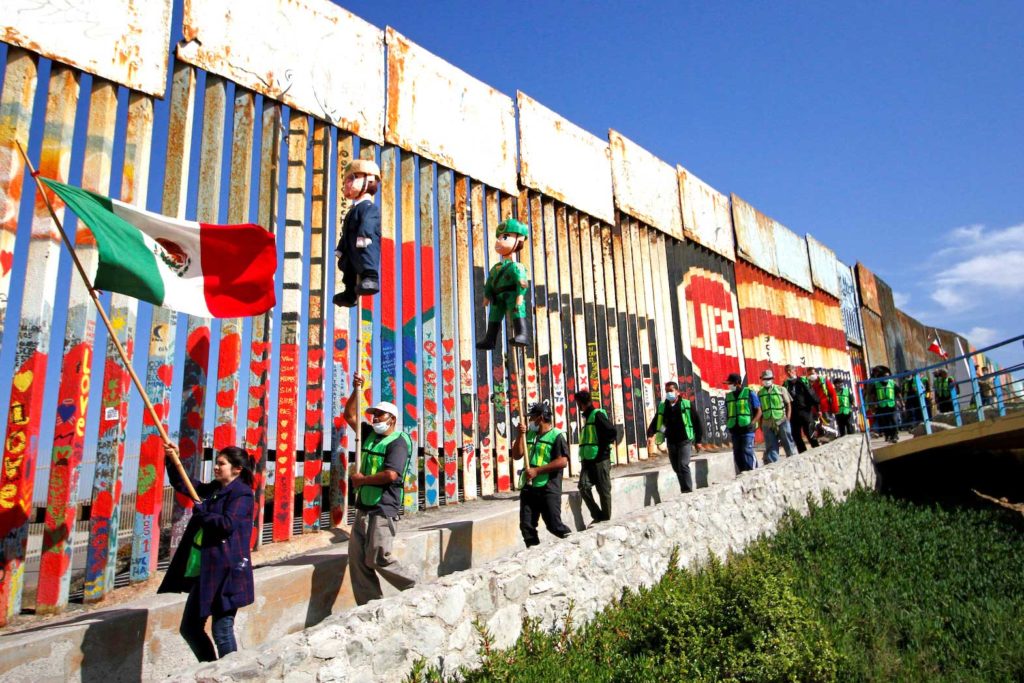 Migrants and members of civil society hold pinatas in the image of U.S. President Donald Trump and a border patrol officer during a protest against stalled asylum claims and the building of the wall, at the border fence between Mexico and the U.S. in Tijuana, Mexico October 31, 2020. REUTERS/Jorge Duenes/File Photo