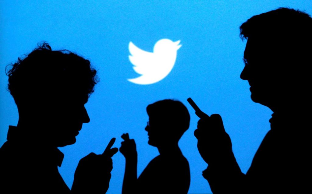 People holding mobile phones are silhouetted against a backdrop projected with the Twitter logo in this illustration picture taken September 27, 2013. REUTERS/Kacper Pempel/Illustration/File Photo/File Photo