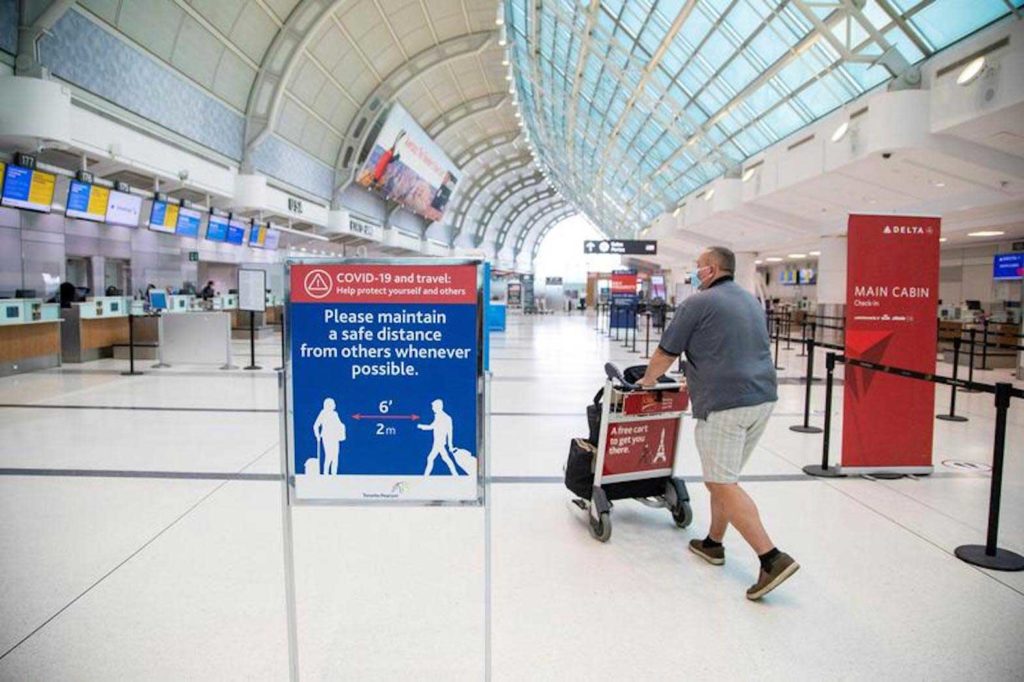 A man pushes a baggage cart wearing a mandatory face mask at Toronto Pearson International Airport in Toronto, Ontario, Canada June 23, 2020. REUTERS/Carlos Osorio/File Photo
