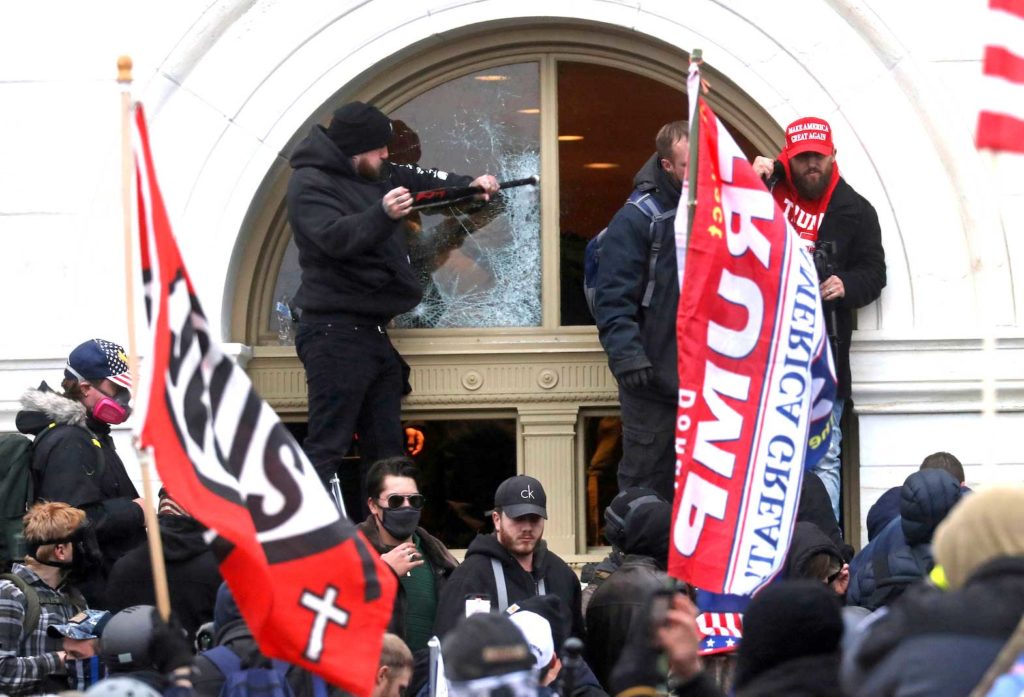  A man breaks a window as a mob of supporters of U.S. President Donald Trump storm the U.S. Capitol Building in Washington, U.S., January 6, 2021. REUTERS/Leah Millis/File Photo