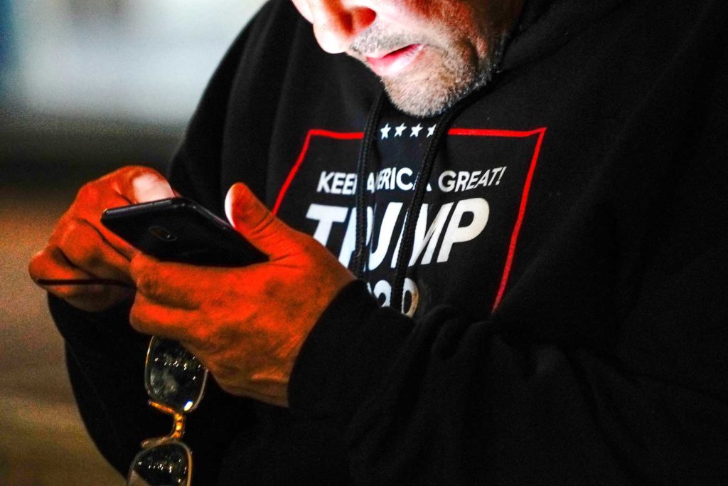  A man wearing a "Trump 2020" sweatshirt uses his mobile phone during a "Stop the Steal" protest outside Milwaukee Central Count the day after Milwaukee County finished counting absentee ballots, in Milwaukee, Wisconsin, U.S. November 5, 2020. REUTERS/Bing Guan/File Photo