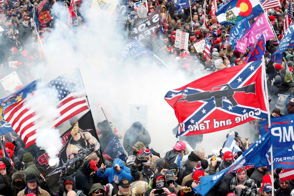 Tear gas is released into a crowd of protesters, with one wielding a Confederate battle flag that reads "Come and Take It," during clashes with Capitol police at a rally to contest the certification of the 2020 U.S. presidential election results by the U.S. Congress, at the U.S. Capitol Building in Washington, U.S, January 6, 2021. REUTERS/Shannon Stapleton