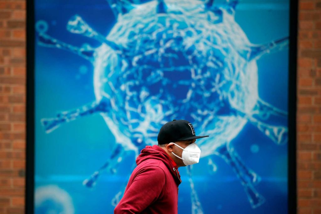 A man wearing a protective face mask walks past an illustration of a virus outside a regional science center, as the city and surrounding areas face local restrictions in an effort to avoid a local lockdown being forced upon the region, amid the coronavirus disease (COVID-19) outbreak, in Oldham, Britain August 3, 2020. REUTERS/Phil Noble