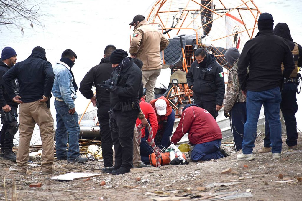 Paramedics check the body of a Honduran migrant child, who drowned while crossing the frigid waters of the Rio Grande river from Mexico into the U.S. with his mother and sister, according to local media, in Piedras Negras, Mexico February 17, 2021. REUTERS/Stringer