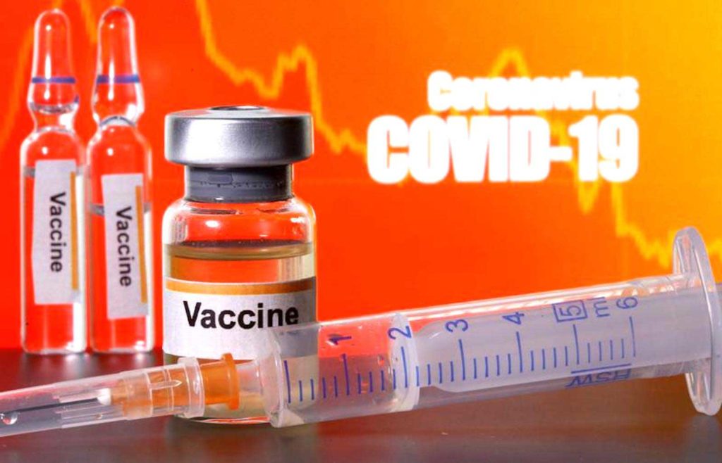 Small bottles labelled with "Vaccine" stickers stand near a medical syringe in front of displayed "Coronavirus COVID-19" words in this illustration taken April 10, 2020. REUTERS/Dado Ruvic/Illustration/File Photo