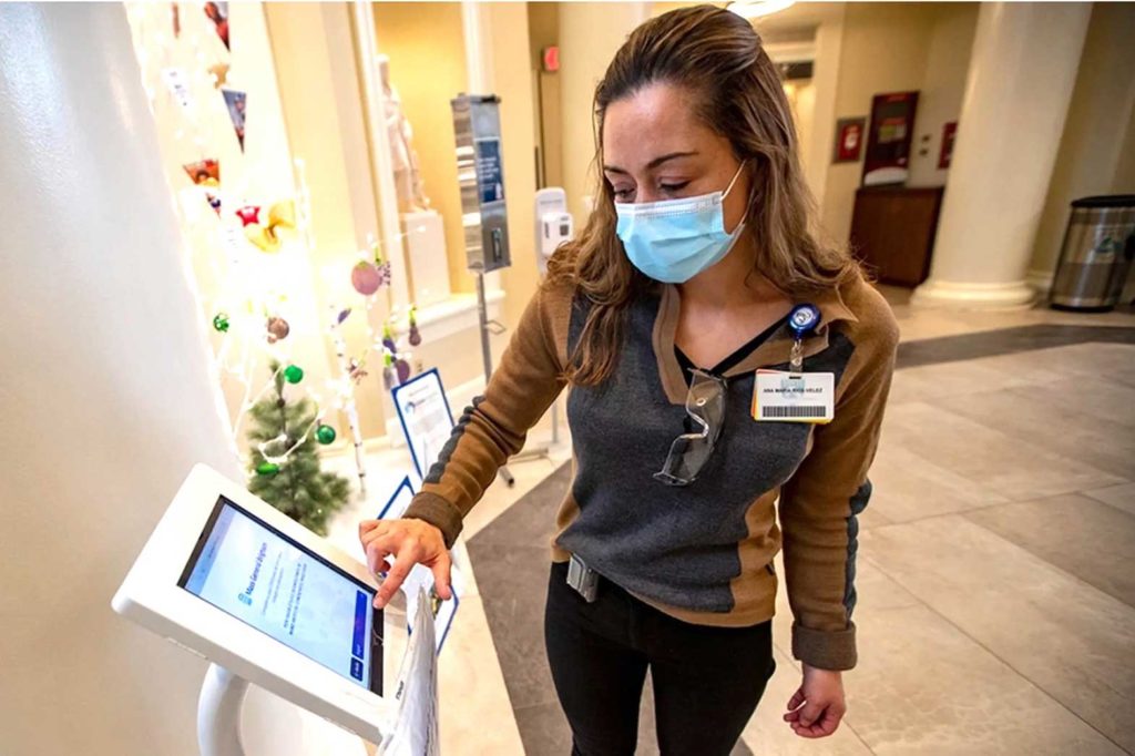 Interpreter Ana Maria Rios-Velez demonstrates the screening app at the front entrance of Brigham and Women’s Hospital in Boston. It has a multilingual function to better communicate with non-English-speaking patients and staffers.  (JESSE COSTA / WBUR)