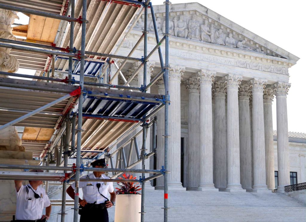 U.S. Supreme Court police officers take shelter from the sun under a construction platform outside the court building in Washington, U.S. June 7, 2021. REUTERS/Jonathan Ernst/File Photo
