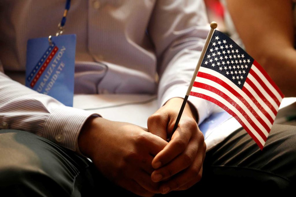 A new citizen holds a U.S. flag at the U.S. Citizenship and Immigration Services (USCIS) naturalization ceremony at the New York Public Library in Manhattan, New York, U.S., July 3, 2018. REUTERS/Shannon Stapleton