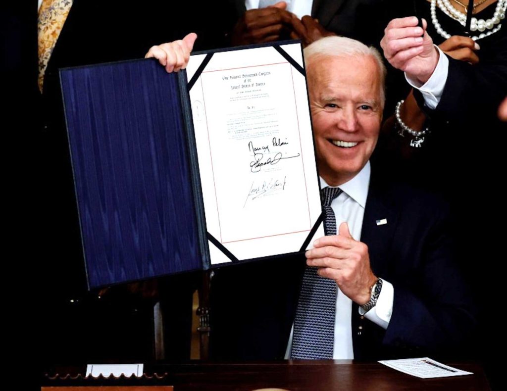  U.S. President Joe Biden is applauded as he holds the Juneteenth National Independence Day Act during a signing ceremony in the East Room of the White House in Washington, U.S., June 17, 2021. REUTERS/Carlos Barria