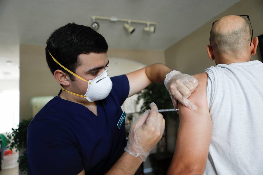 Ledsiel Garcia, a pharmacy technician with DeliveRxd Pharmacy based in Tampa, administers the Pfizer-BioNTech coronavirus disease (COVID-19) vaccine to Mike Payne, a federal employee, at his home in St. Petersburg, Florida, U.S., July 30, 2021. REUTERS/Octavio Jones