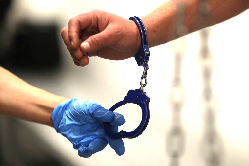 A U.S. Immigration and Customs Enforcement's (ICE) Fugitive Operations Agent takes handcuffs off before booking an immigrant in Los Angeles, California, U.S., March 1, 2020. REUTERS/Lucy Nicholson