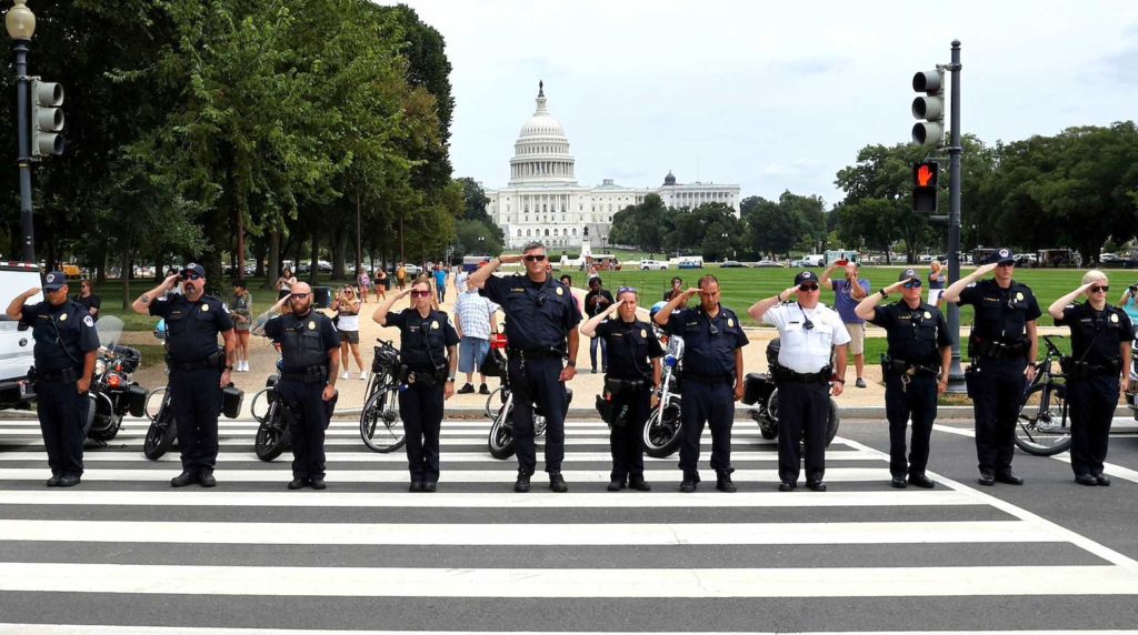Law enforcement officers from Washington's Metropolitan Police Department, the U.S. Capitol Police, the Pentagon Force Protection Agency and other police departments salute as a ceremonial procession in honor of a police officer wounded in a shooting at the Pentagon earlier in the day passes the U.S. Capitol in Washington, August 3, 2021. REUTERS/Jim Bourg