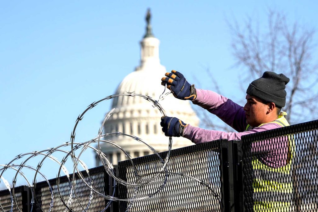  A worker removes razor wire from the top of security fencing as part of a reduction in heightened security measures taken after the January 6th attack on the U.S. Capitol in Washington, U.S., March 20, 2021. REUTERS/Joshua Roberts