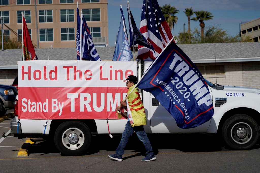 A protester caries a "Trump 2020" flag as Arizona electors gather to cast their votes for the U.S. presidential election, at the Arizona Capitol, in Phoenix, Arizona, U.S., December 14, 2020. REUTERS/Cheney Orr