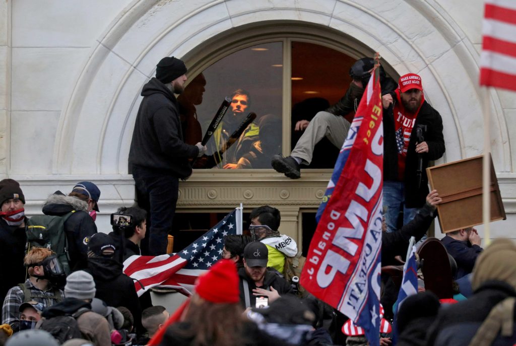 A mob of supporters of then-U.S. President Donald Trump climb through a window they broke as they storm the U.S. Capitol Building in Washington, U.S., January 6, 2021. REUTERS/Leah Millis/File Photo