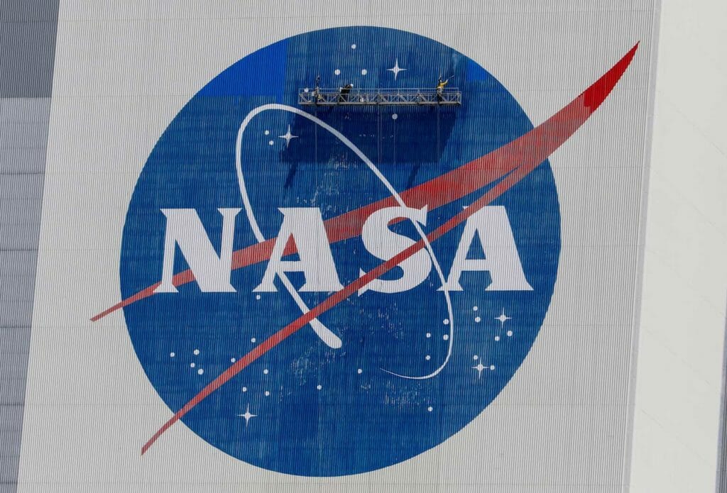 Workers pressure wash the logo of NASA on the Vehicle Assembly Building before SpaceX will send two NASA astronauts to the International Space Station aboard its Falcon 9 rocket, at the Kennedy Space Center in Cape Canaveral, Florida, U.S., May 19, 2020. REUTERS/Joe Skipper