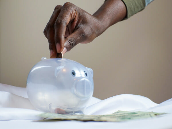 This is a person putting coins into a piggy bank.