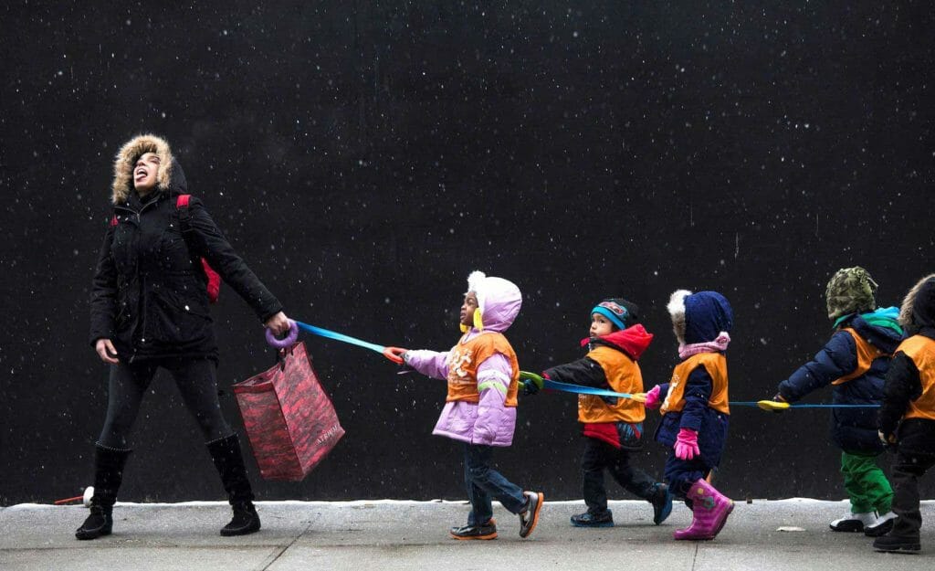 A schoolteacher, who wished to stay unidentified, attempts to catch snowflakes while leading her students to a library from school in the Harlem neighborhood, located in the Manhattan borough of New York on January 10, 2014. REUTERS/Adrees Latif/File Photo