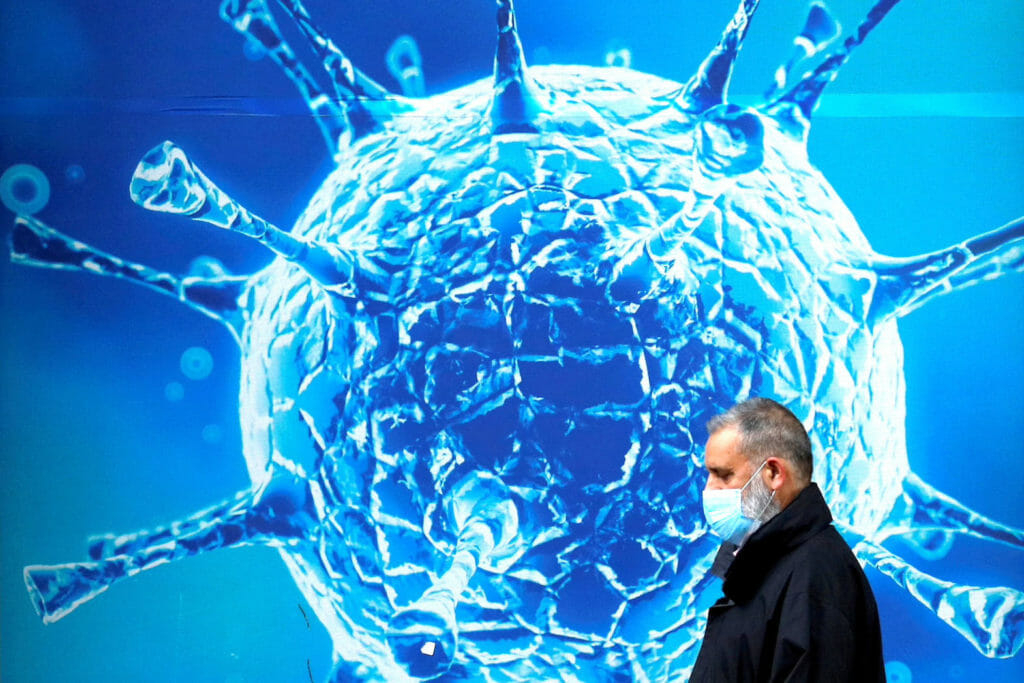  A man wearing a protective face mask walks past an illustration of a virus outside a regional science centre amid the coronavirus disease (COVID-19) outbreak, in Oldham, Britain August 3, 2020. REUTERS/Phil Noble