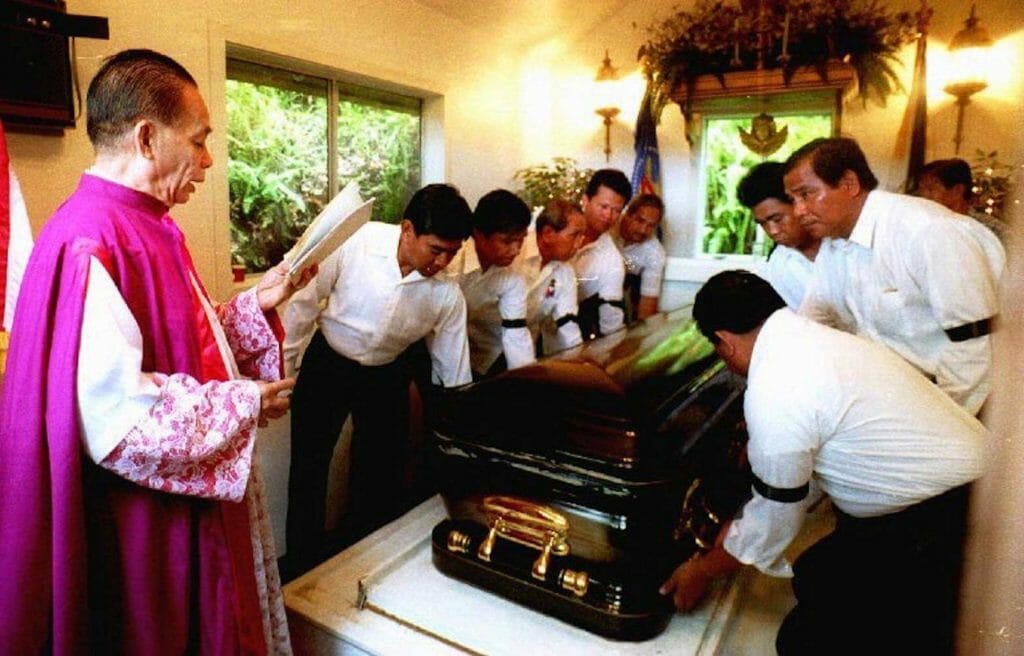 Monsignor Domingo Nebres (L) reads his benediction in Hawaii as the body of the late Philippine President Ferdinand Marcos is removed 01 September 1993 from the mausoleum where he lay in state since dying in exile in 1989. Marcos' body is scheduled to be returned to the Philippines on 05 September. GEORGE LEE/AFP 