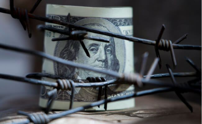 These is a 100-dollar bill behind barbed wires.