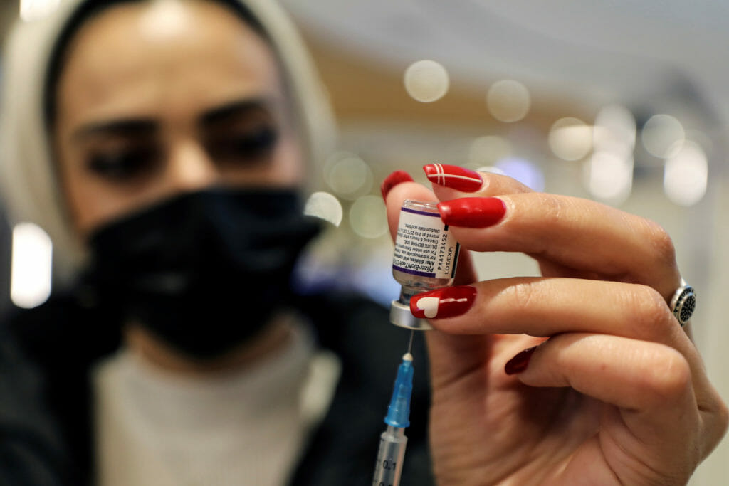 A health worker prepares a dose of Pfizer-BioNTech's coronavirus disease (COVID-19) vaccine as the COVID-19 vaccination campaign continues amid talks of a fourth dose for high-risk groups including those over the age of 60, in Malcha shopping mall, Jerusalem, December 22, 2021. REUTERS/Ammar Awad