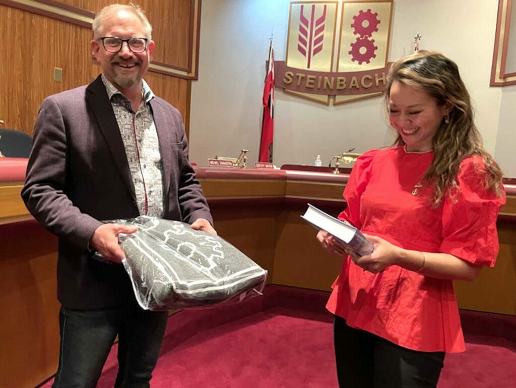  Steinbach Mayor Earl Funk presents MP Rechie Valdez with gifts to help her remember her visit to the city -- a pin representing the Automobile City, a book on the history of Steinbach, and a Steinbach themed blanket. CONTRIBUTED