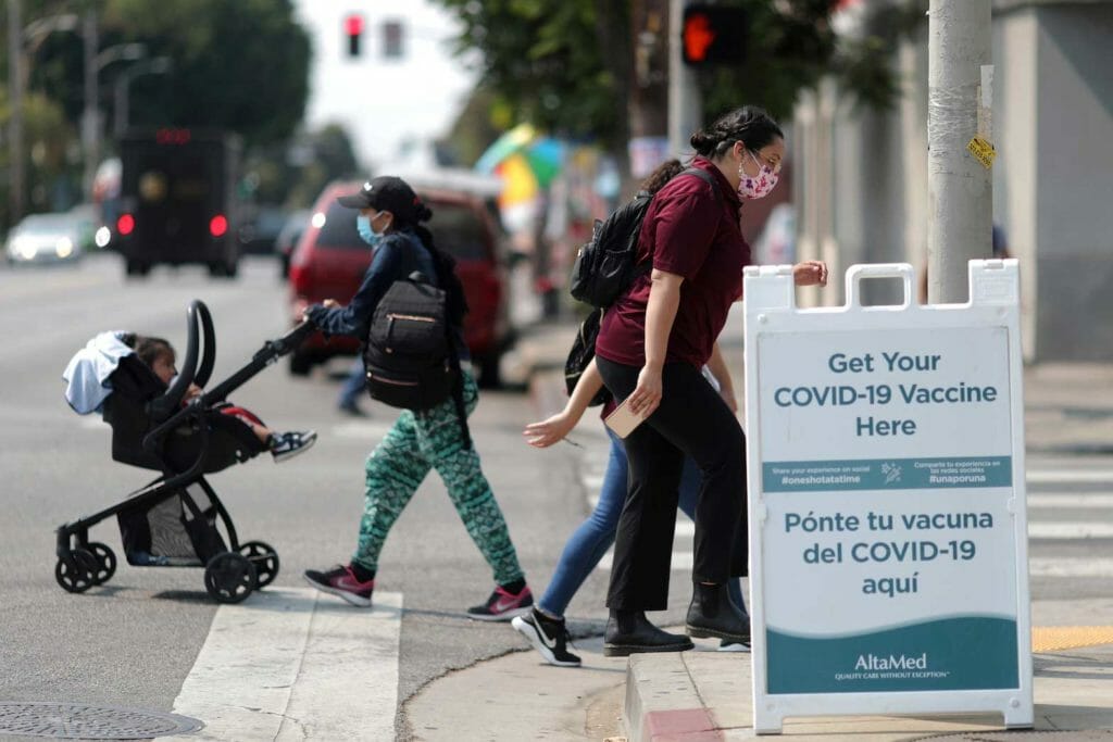 People walk past a sign for a coronavirus disease (COVID-19) vaccination clinic in Los Angeles, California, U.S., August 17, 2021. REUTERS/Lucy Nicholson/File Photo