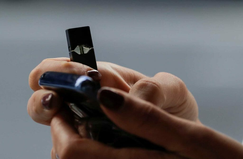 A woman holds a Juul e-cigarette while walking in New York, U.S., September 27, 2018. REUTERS/Brendan McDermid