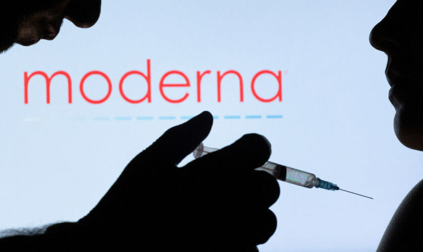 People pose with syringe with needle in front of displayed Moderna logo in this illustration taken, December 11, 2021. REUTERS/Dado Ruvic/Illustration/Files