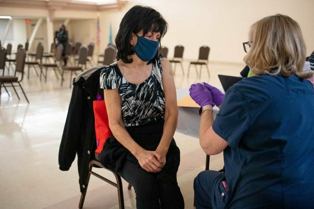A resident that is 50 years old and immunocompromised converses with the nurse after receiving a second booster shot of the coronavirus disease (COVID-19) vaccine in Waterford, Michigan, U.S., April 8, 2022. REUTERS/Emily Elconin