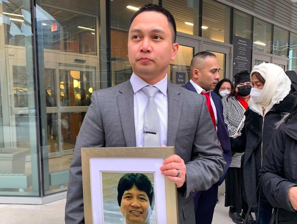 Edward Balaquit with a photo of his missing father, Eduardo, after the sentencing of the latter's killer. SCREENGRAB/CBC