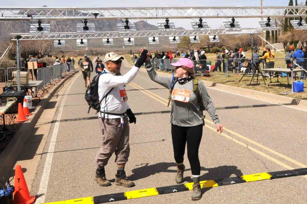 Joe Garbanzos (left) is greeted with a high five upon finishing 14.2 miles at the Bataan Memorial Death March in White Sands, New Mexico. (BMDM Official Photo) 