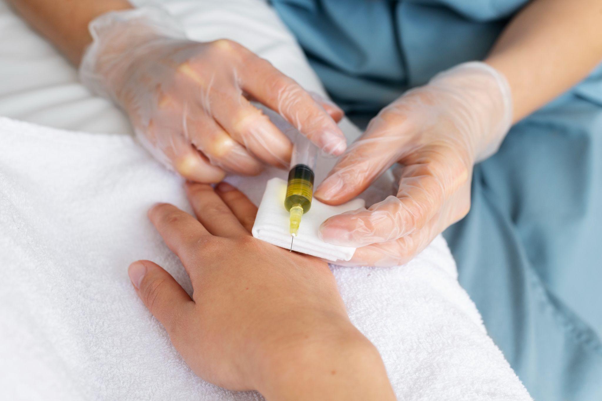 Healthcare provider injecting yellow liquid into a patient's hand for ketamine therapy