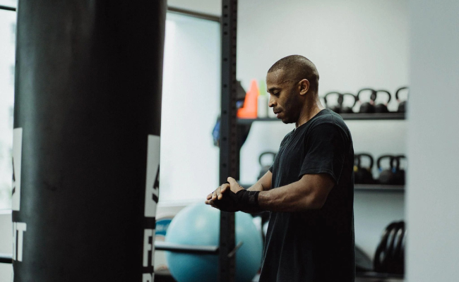 Man preparing wrist wraps in a black oversized workout shirt