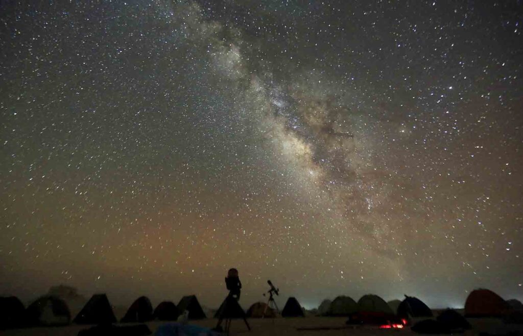 The Milky Way is seen in the night sky around telescopes and camps of people over rocks in the White Desert north of the Farafra Oasis southwest of Cairo May 16, 2015. REUTERS/Amr Abdallah Dalsh
