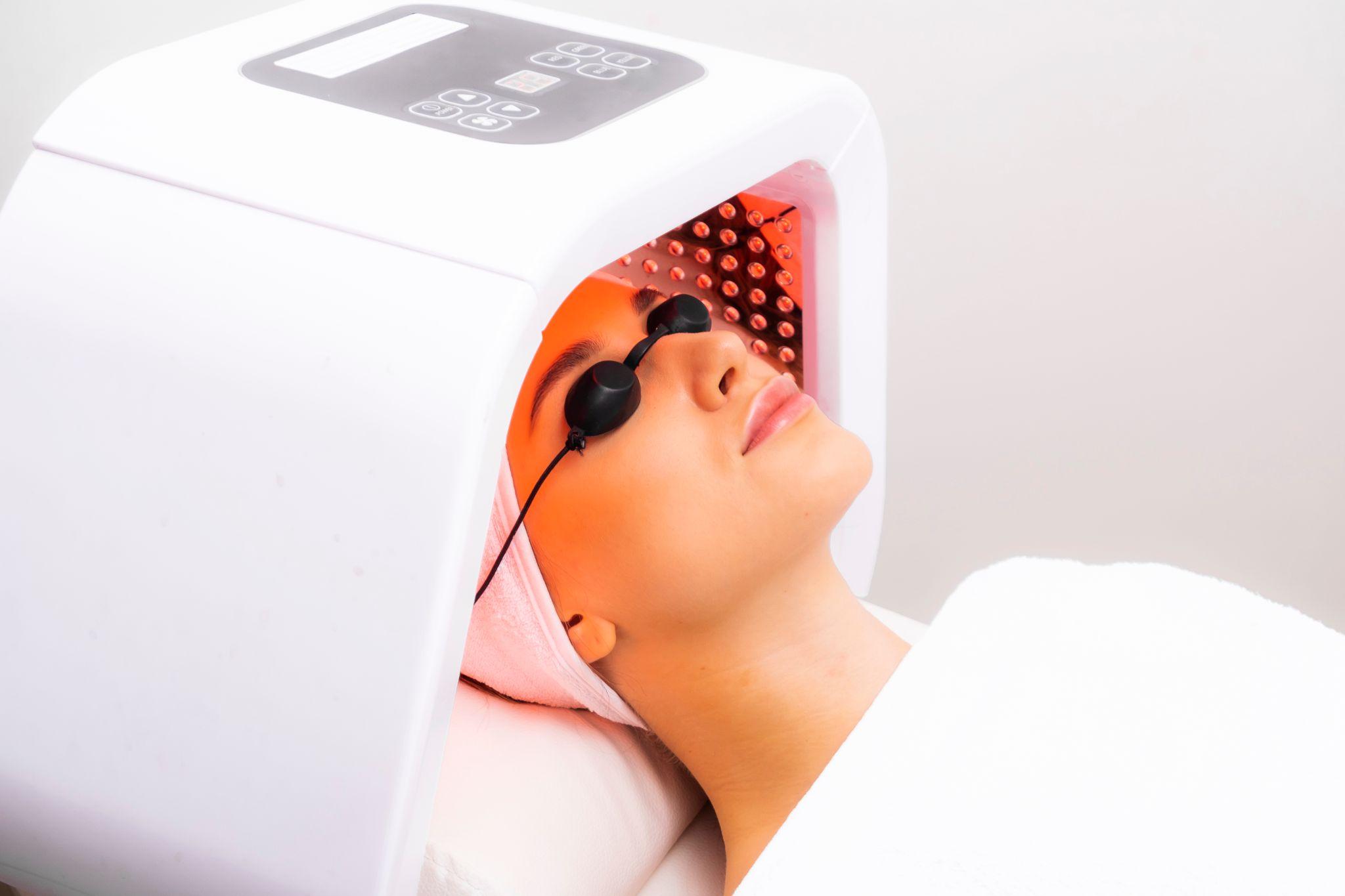 Woman getting a facial with Red Light Therapy Device