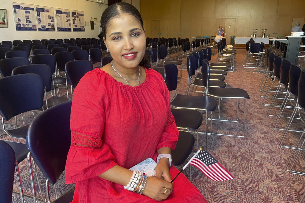US citizenship test changes: Heaven Mehreta, 32, smiles and holds a small American flag inside Mount Zion Temple in St. Paul, Minn. on June 21, 2023, after becoming a US citizen at a naturalization ceremony that day in the synagogue. Mehreta immigrated from Ethiopia 10 years ago, learned English as an adult, and passed the US citizenship test in May