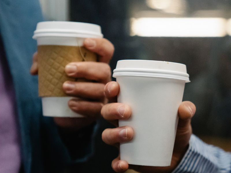 A compostable coffee cup made from compostable materials with a brown sleeve