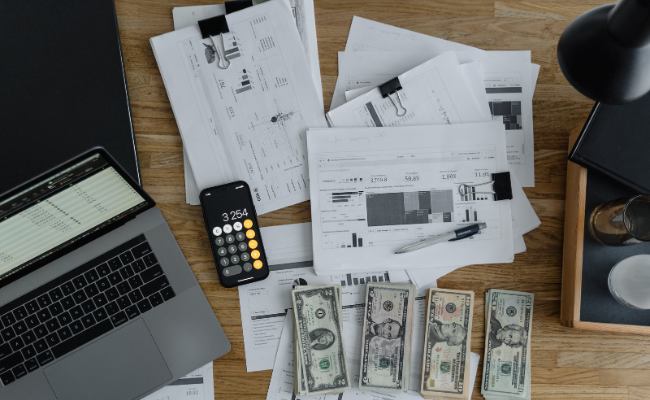 Money and laptop spread over bills